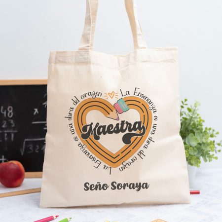 Tote bag personalizada con el texto ‘Maestra' y ‘La enseñanza es una obra del corazón', nombre de la profesora, curso y nombres de los niños en el reverso