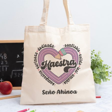 Tote bag personalizada con el texto Maestra y los adjetivos ‘Comprensiva, cariñosa, dedicada, confiable, cálida, leal y amable', nombre de la profesora, curso y nombres de los niños en el reverso